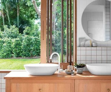 A bathroom with a large window looking out onto greenery