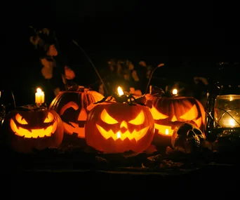 Four carved pumpkins with candles inside and some other spooky Halloween decorations