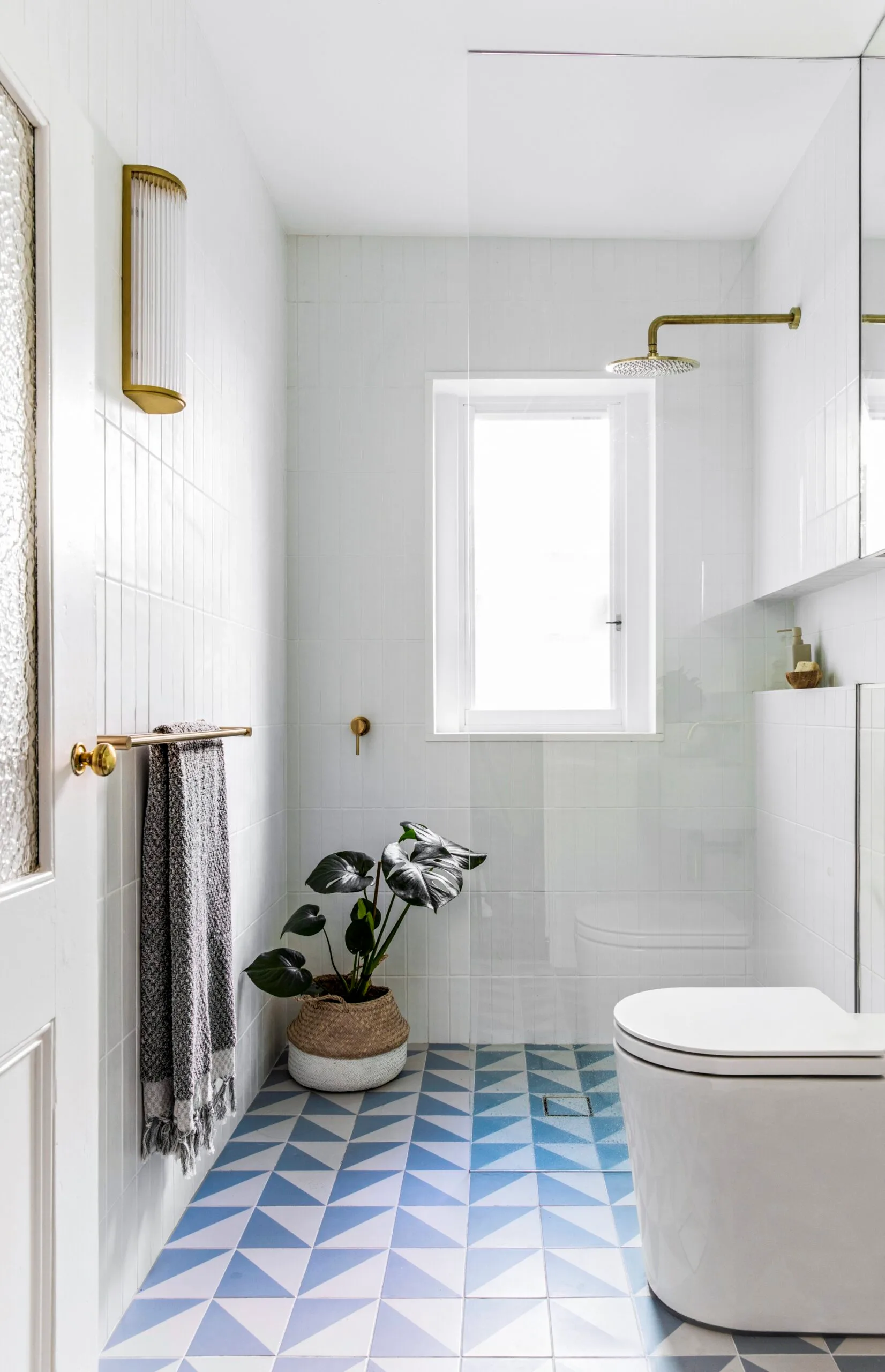 A white bathroom with blue and white tiles and gold fittings
