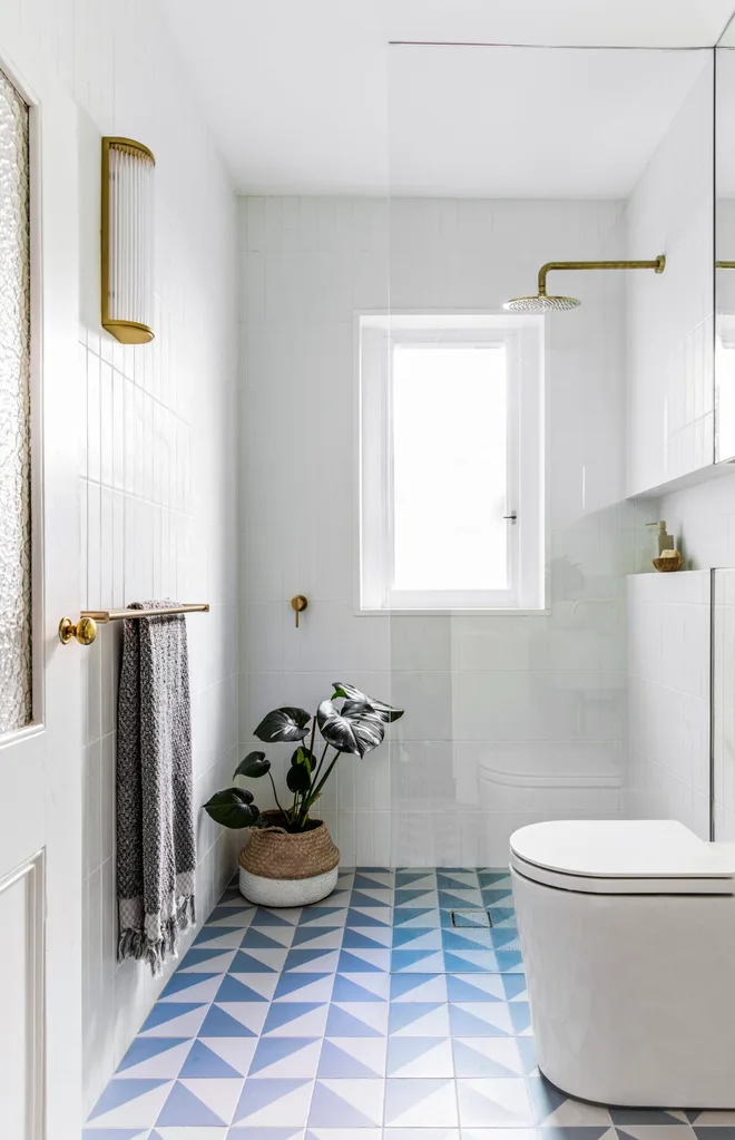 A white bathroom with blue and white tiles and gold fittings