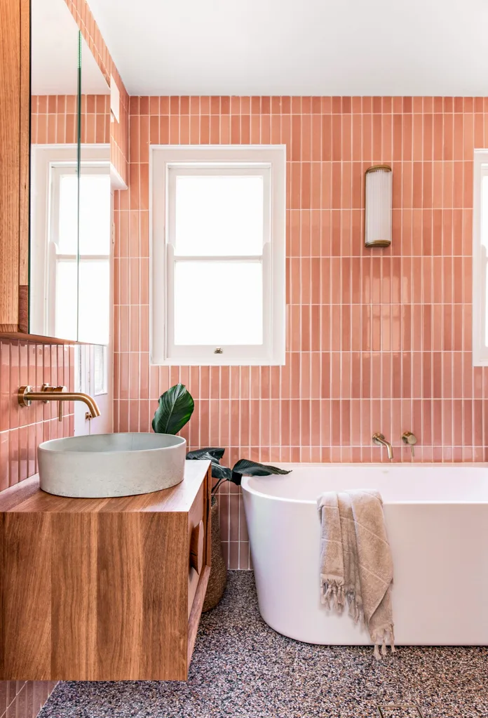 A bathroom with pink tiling and a timber floating vanity