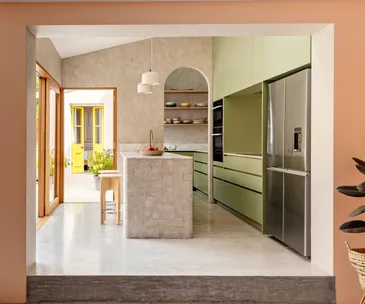 Pink walls frame a grey and green kitchen with concrete floors