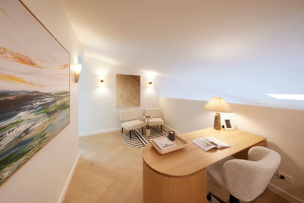 An office area with a curved timer desk and two white sitting chairs