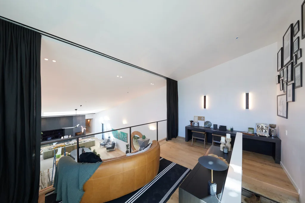 A mezzanine lounge space with a gallery wall and a leather couch