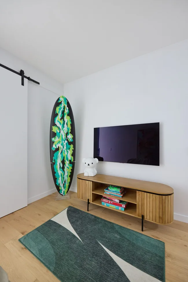 A TV space with a small green rug and a green and black surfboard