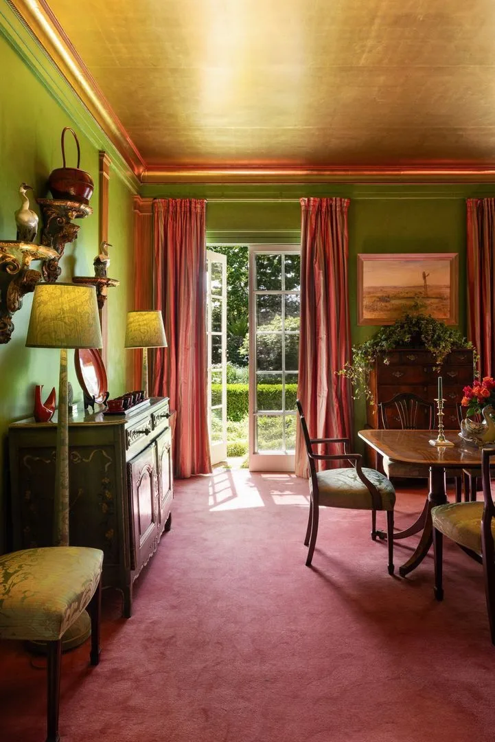 A green formal dining room with red carpeting and drapes