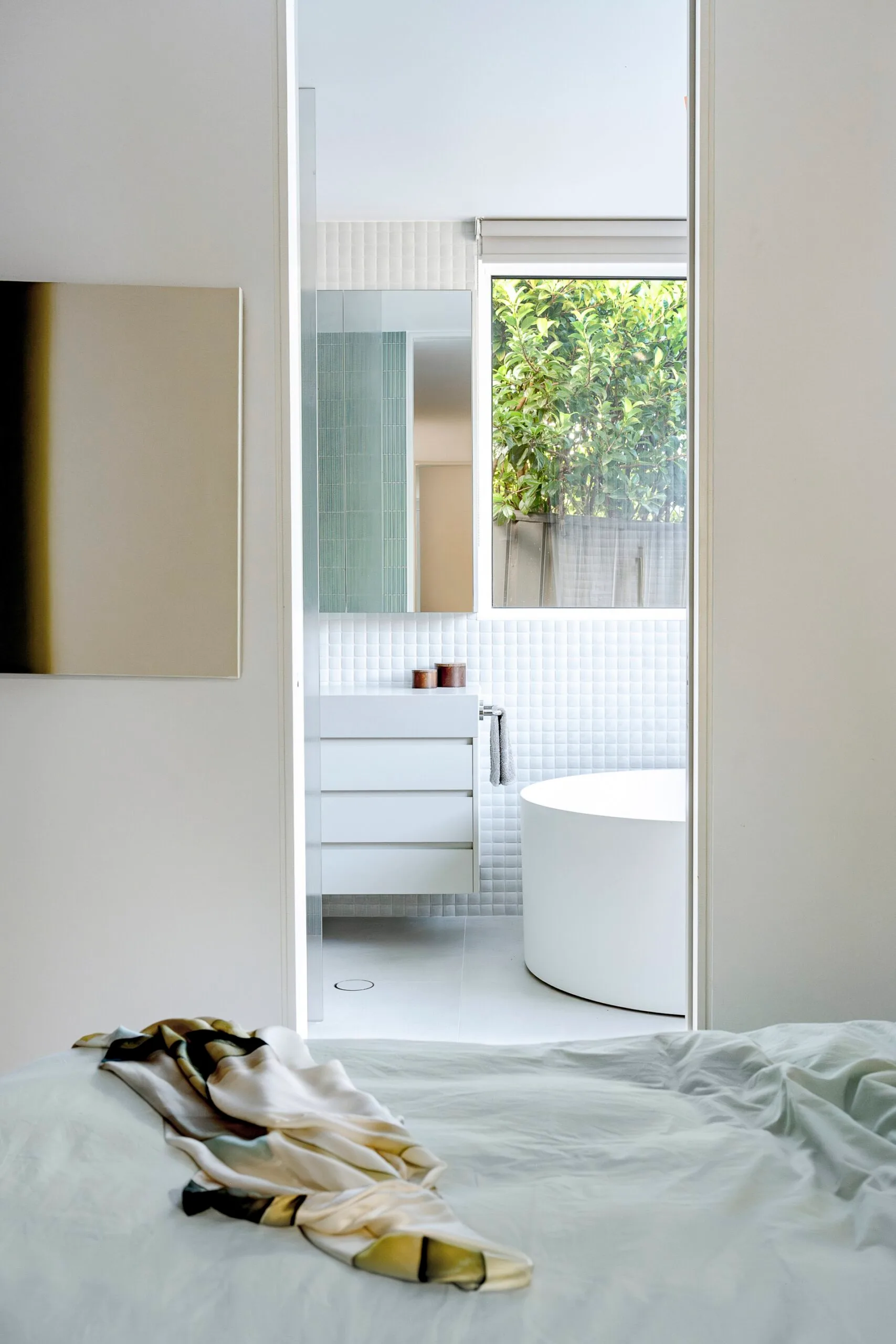 A view from the bedroom into the white ensuite with circular tub