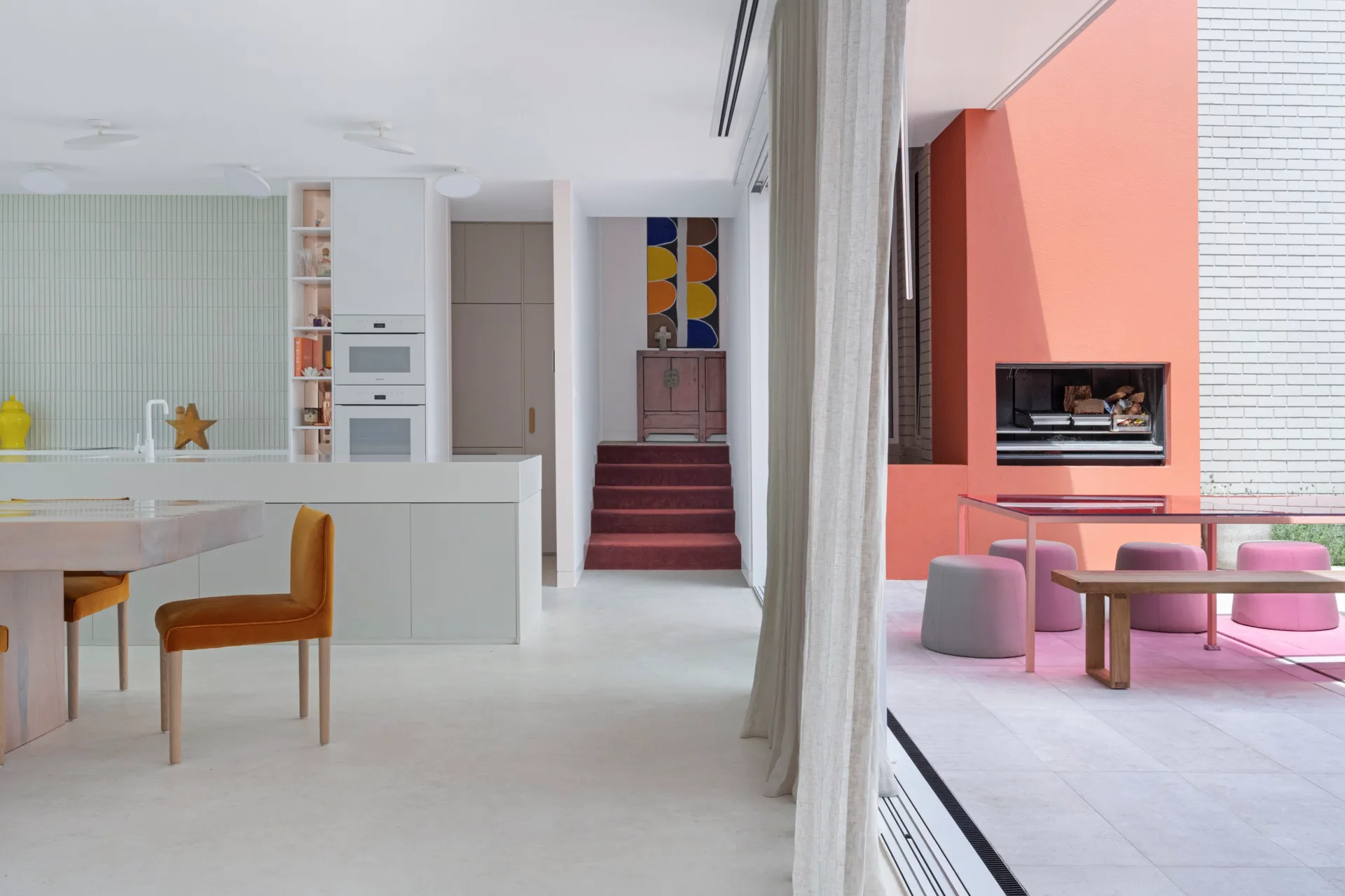 A spacious open-plan living and dining area with concrete floors and colourful accents