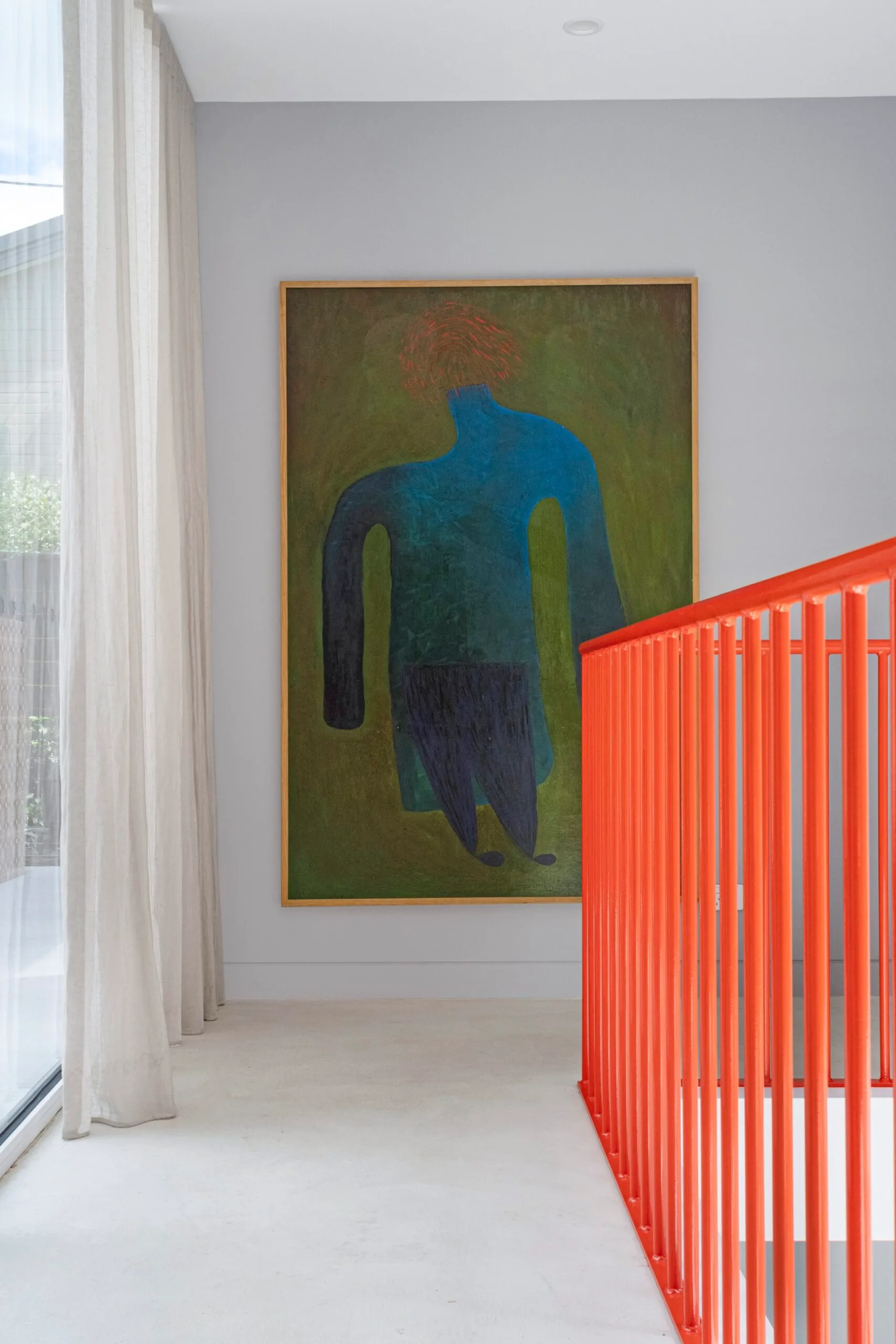 A landing with a large painting and bright orange railings