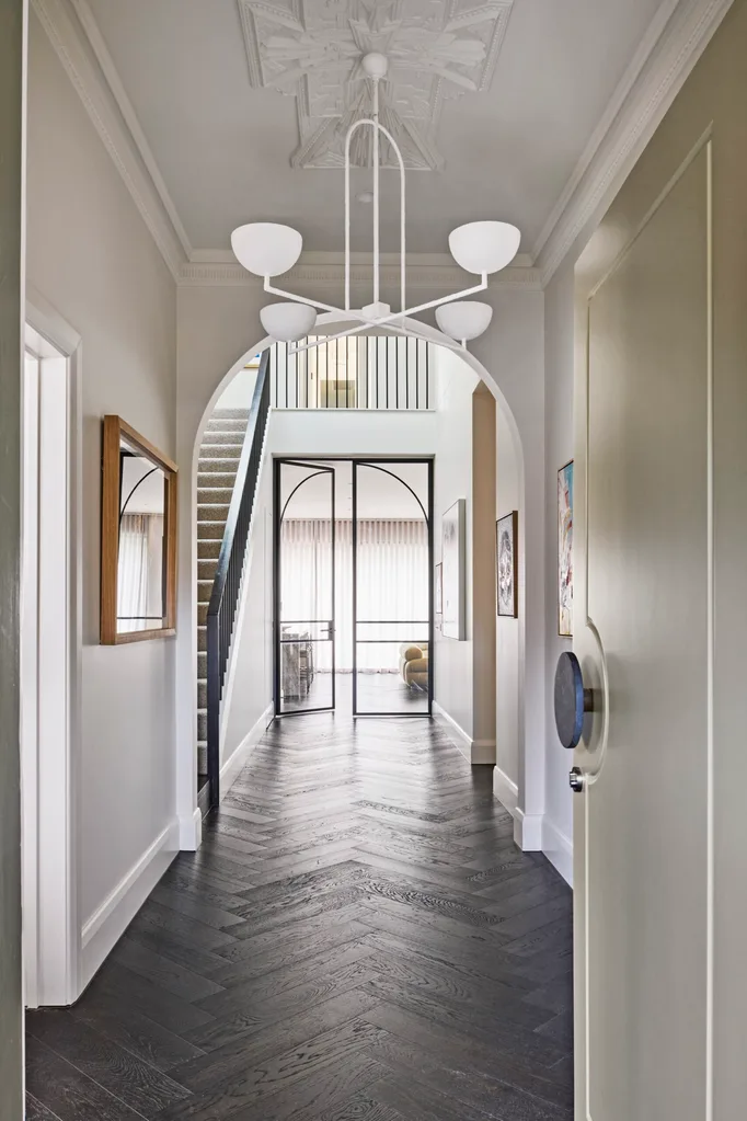 A wide hallway with parquetry flooring and decorative ceiling details.