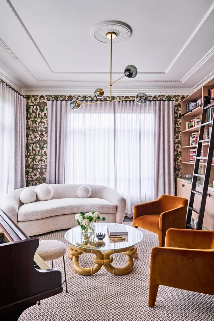 A lounge area with orange armchairs, whimsical wallpaper and a piano
