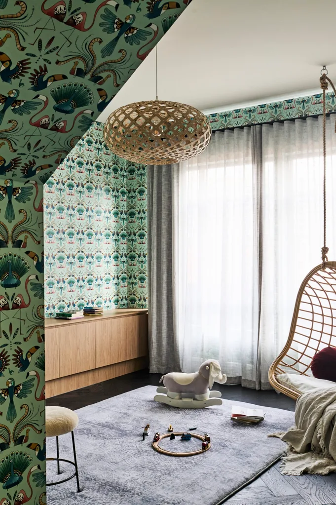 A kids bedroom with green wallpaper and a hanging egg chair