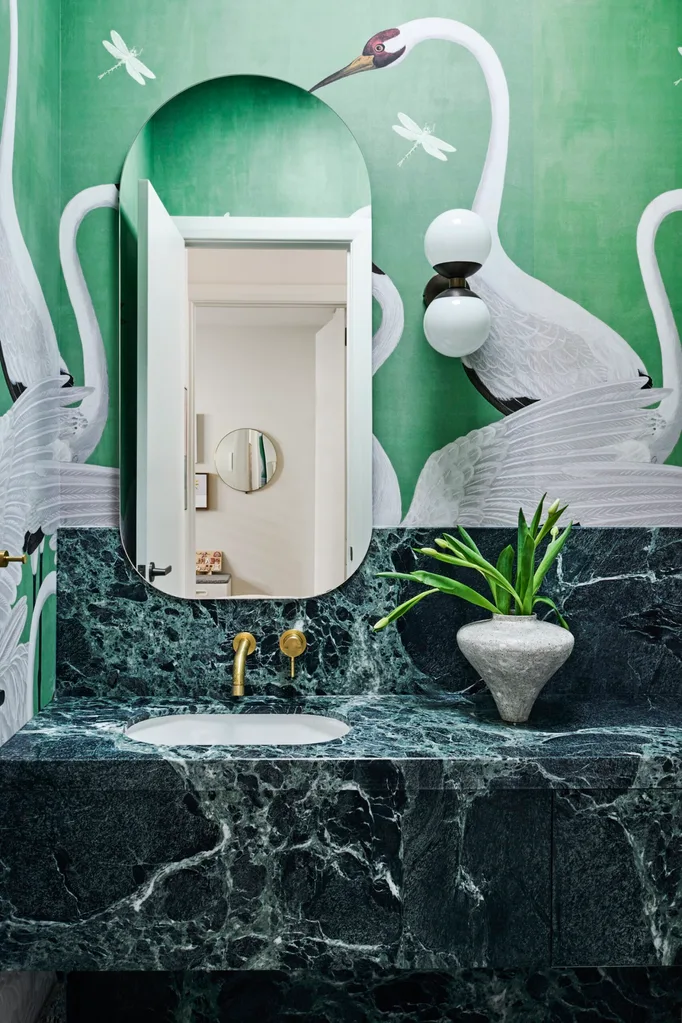 A green powder room with a marble benchtop and crane wallpaper