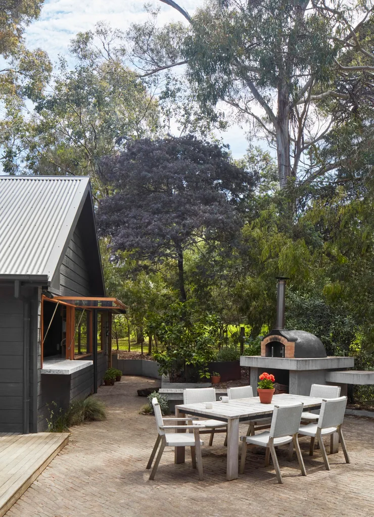 An alfresco space with a pizza oven and timber outdoor dining set