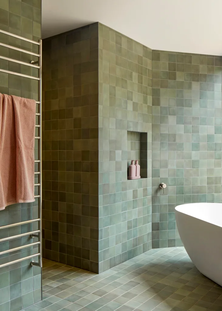 A green-tiled bathroom with a freestanding tub