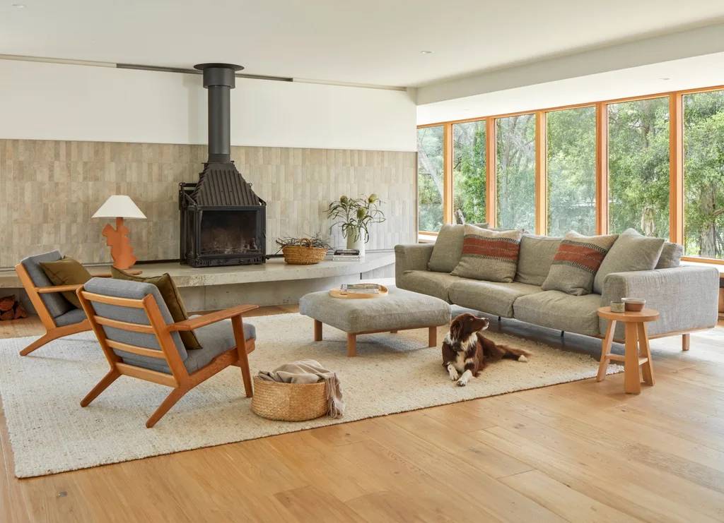 An open-plan living space with floor-to-ceiling windows and a dog laying on a beige rug