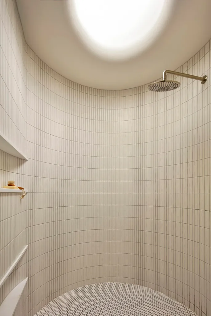 A curved walk-in shower with beige tiles
