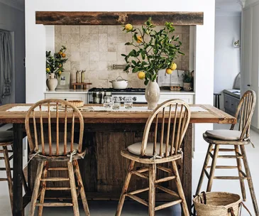 A large wooden kitchen island with rustic stools and a decorate lemon display