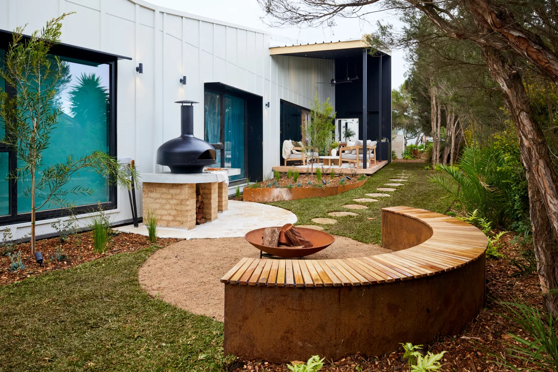 A fire pit with a curved bench seat and a pizza oven.