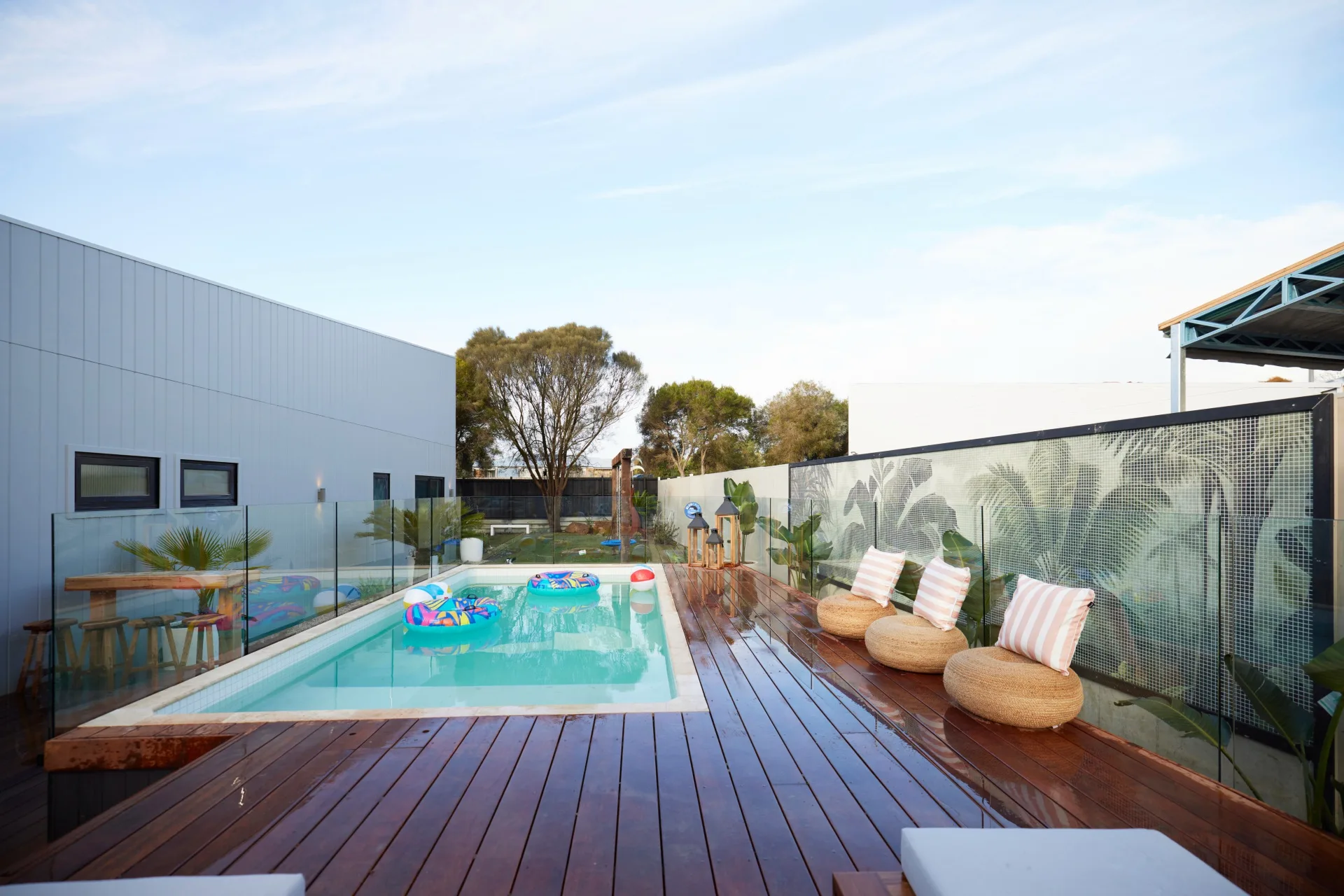 A deck with an above-ground pool with inflatable pool toys and a massive tile mural covering the wall.