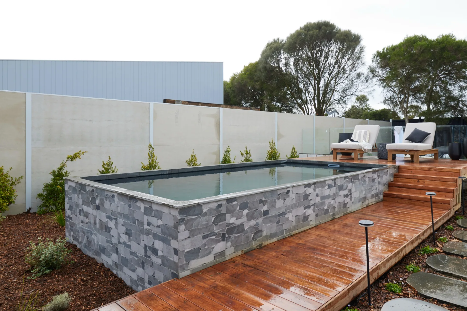 Kylie and Brad's pool with a wooden walkway and two sun loungers