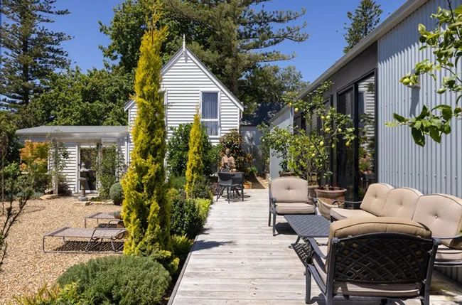 Sunny courtyard of the house with white board and modern extension