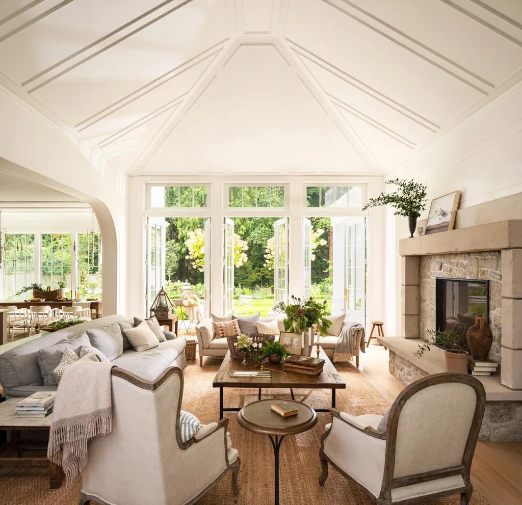 A large living area with a fireplace, a pitched roof and plenty of antique furniture.