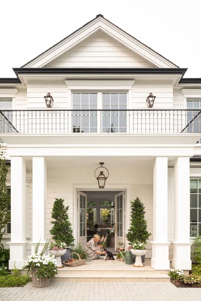 The façade of a large, white house with pillars and a balcony.