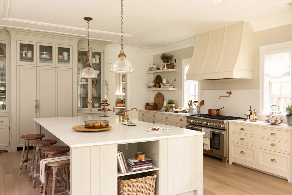 A country-style kitchen with brass accents, a large chrome stove and a massive white kitchen island.