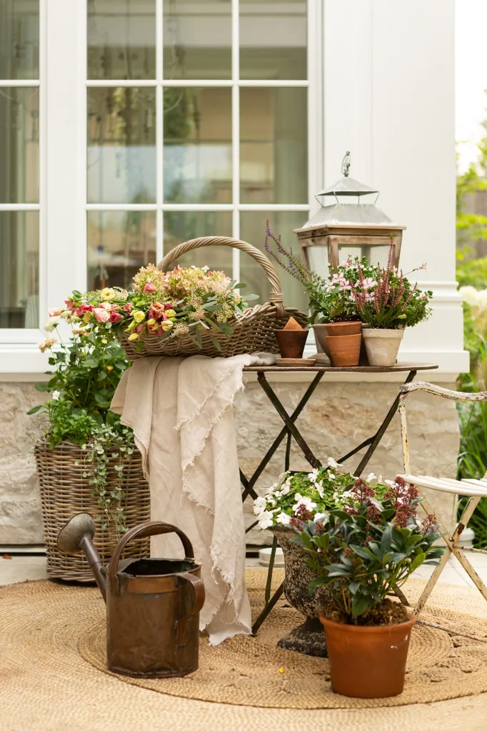 An outdoor table and chairs laden with flowers and plants.