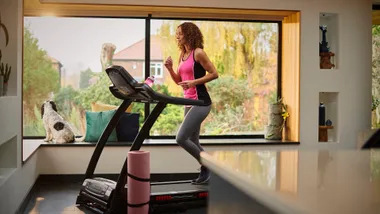 A woman running on a treadmill at home with a lovely view from the windows.