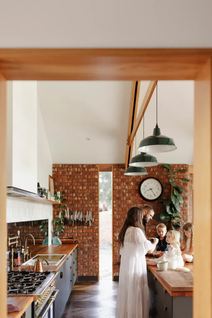 A family in a timber and brick kitchen with country pendant lights
