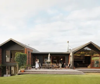 A large family home surrounded by lawn with a material palette of red brick, timber and steel