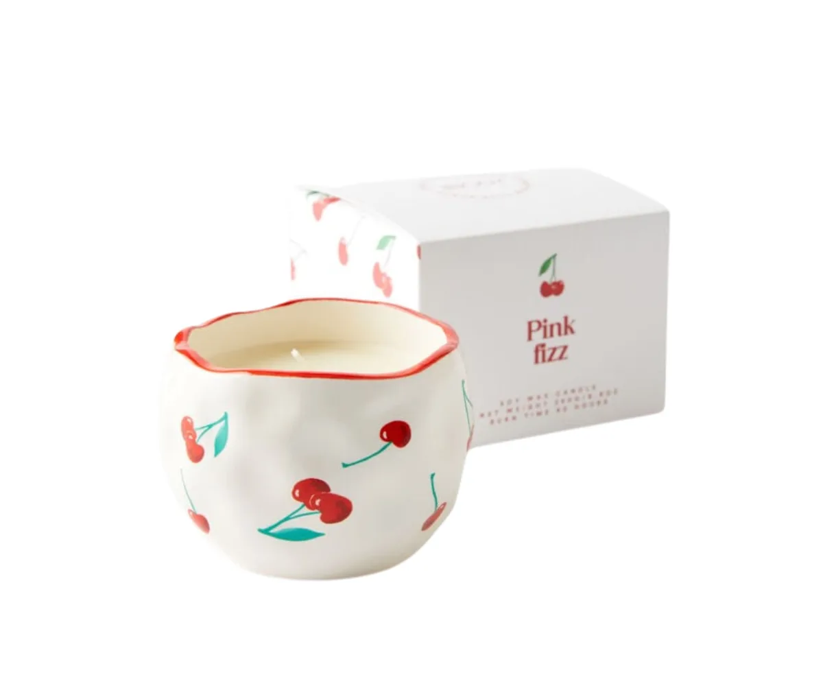 A candle with a cherry painted holder