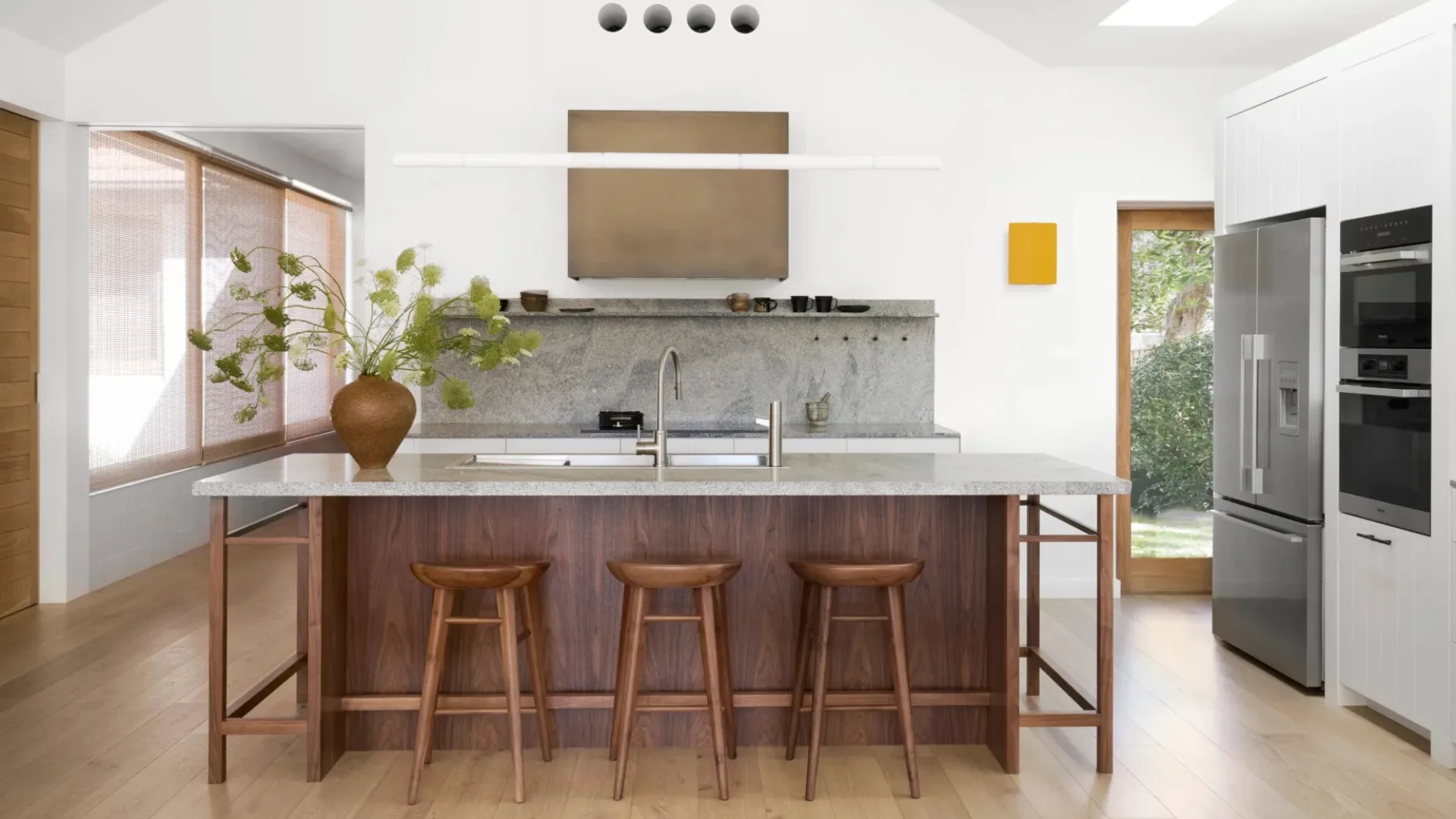 A modern white kitchen with a stone island bench and timber floors