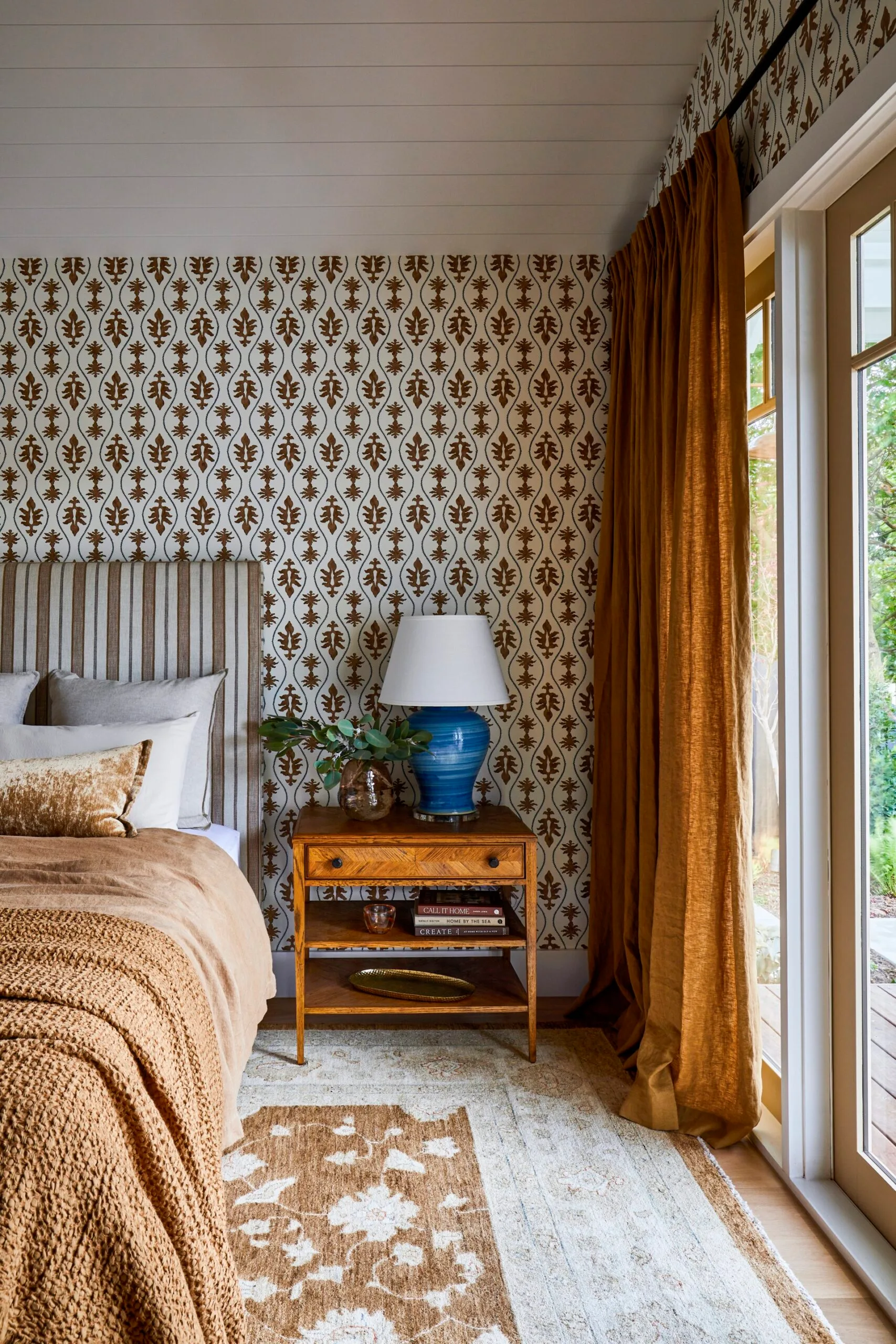 A bold bedroom with wallpaper and mustard accents