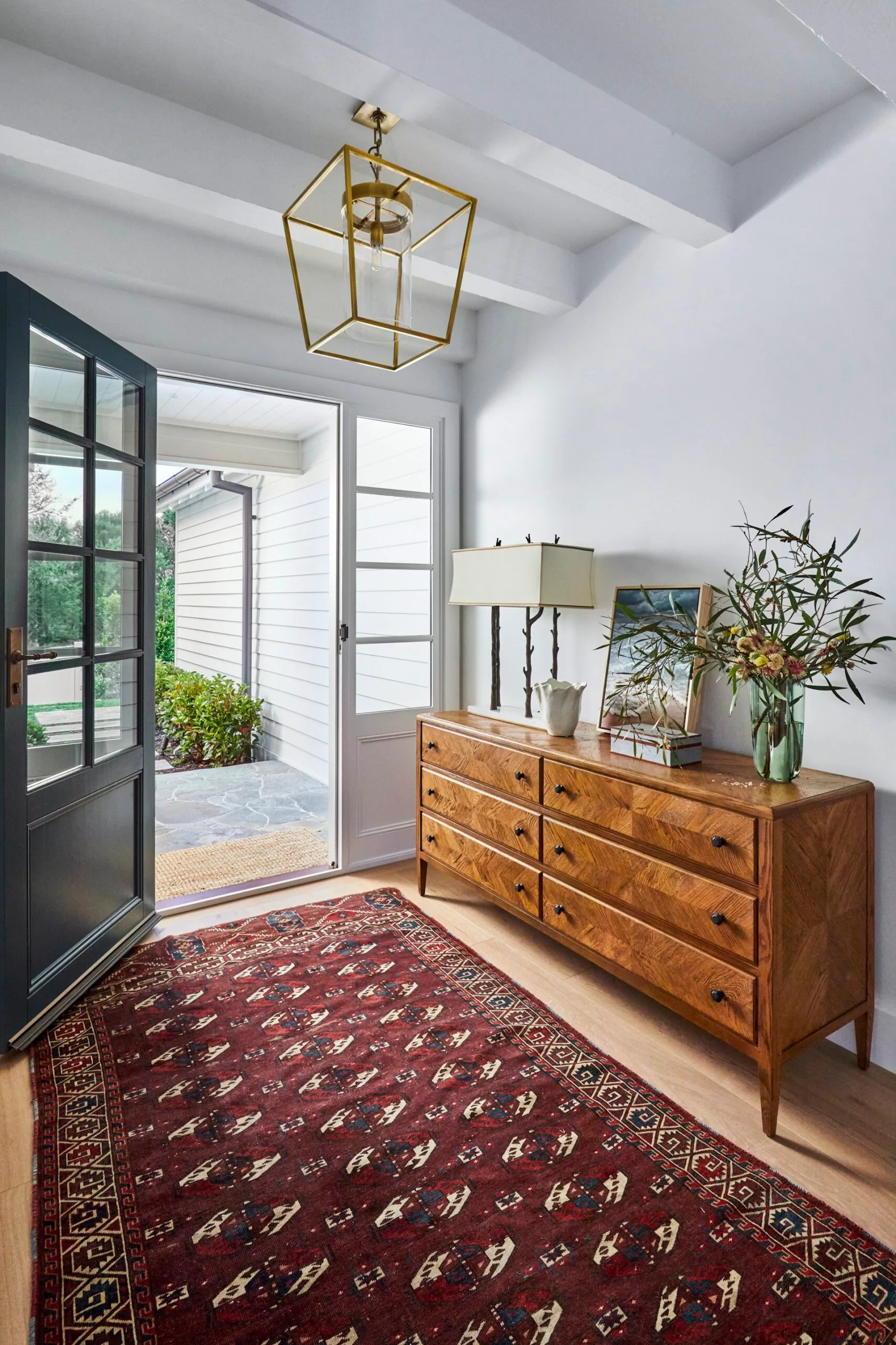 A spacious hallway with a red rug and timber sideboard