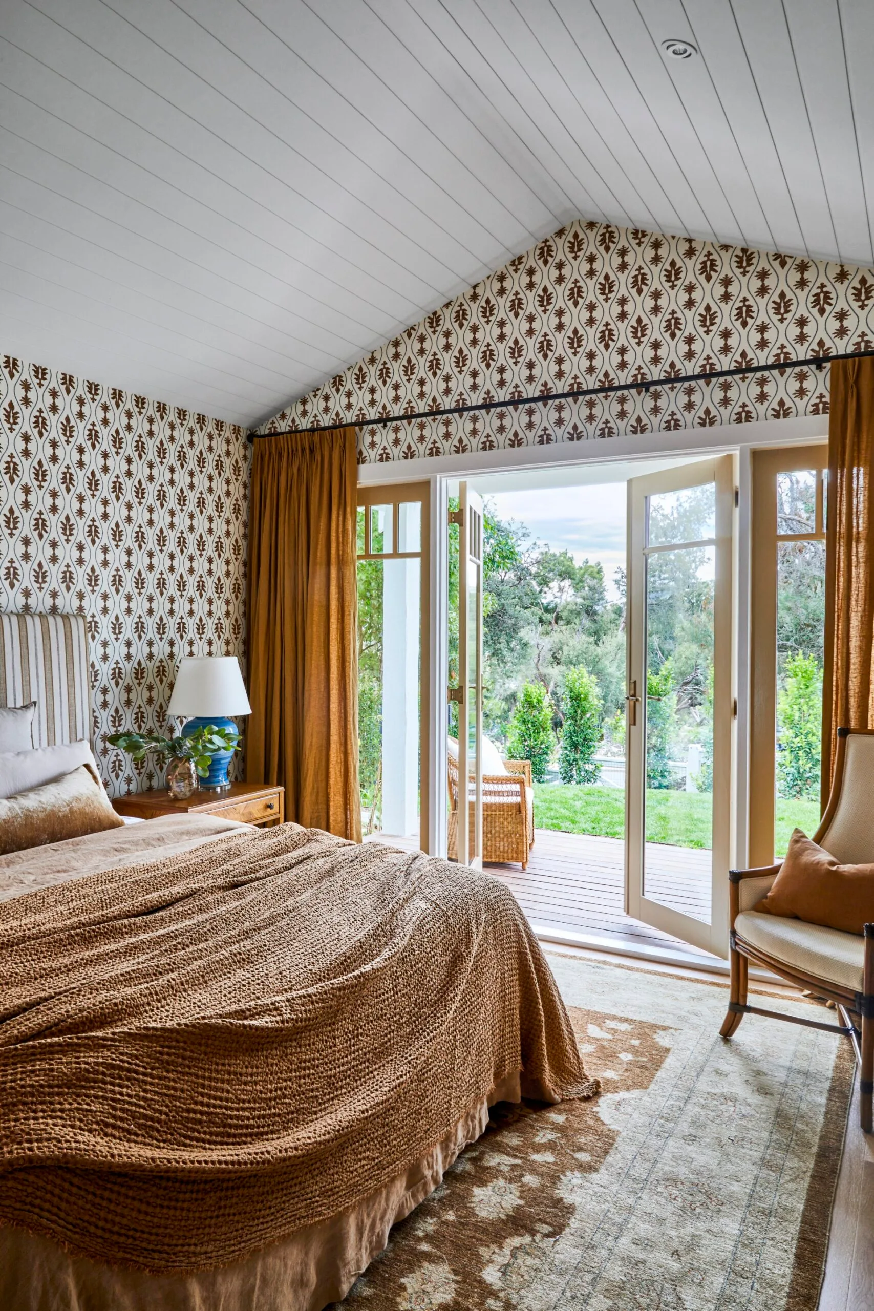 A bold bedroom with wallpaper and mustard accents