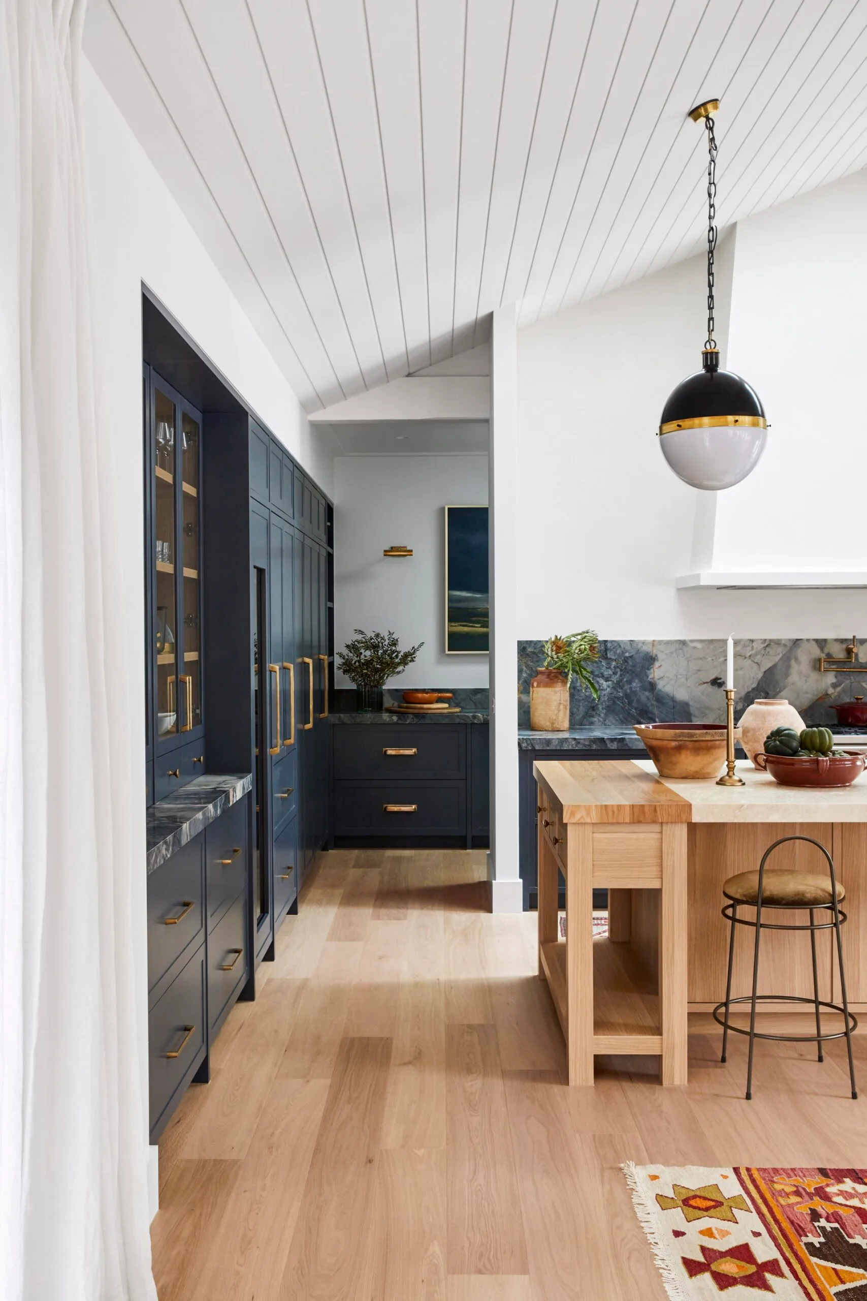 An open-plan living, dining and kitchen area featuring blue cabinetry and timber furnishings