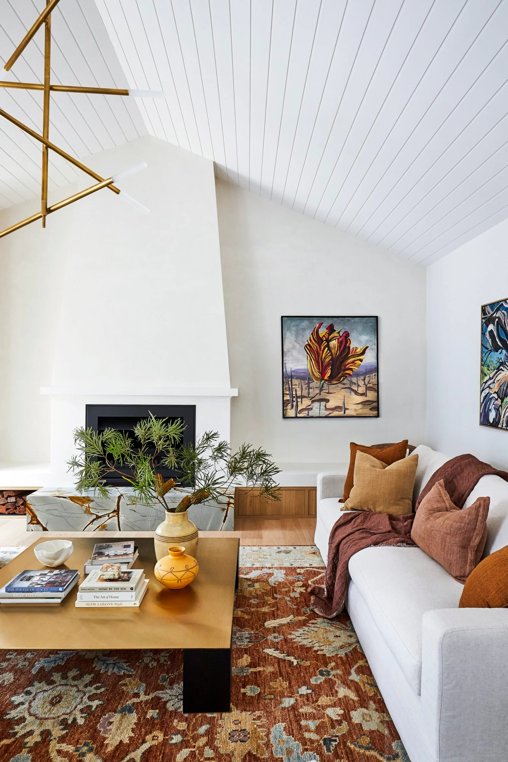 A spacious living space with a fireplace, large orange rug and white sofa