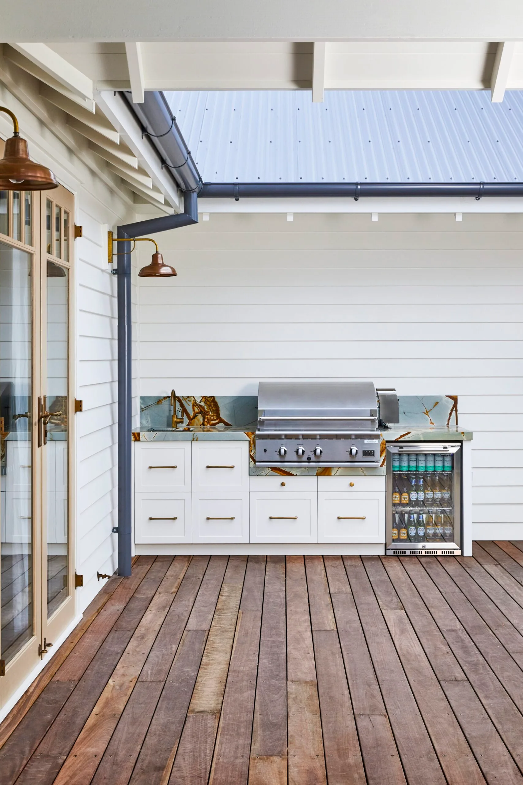 A deck area with an outdoor shower and outdoor kitchen