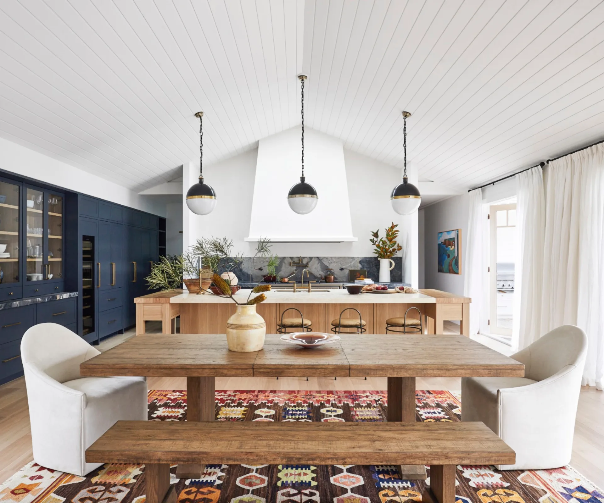 An open-plan living, dining and kitchen area featuring blue cabinetry and timber furnishings