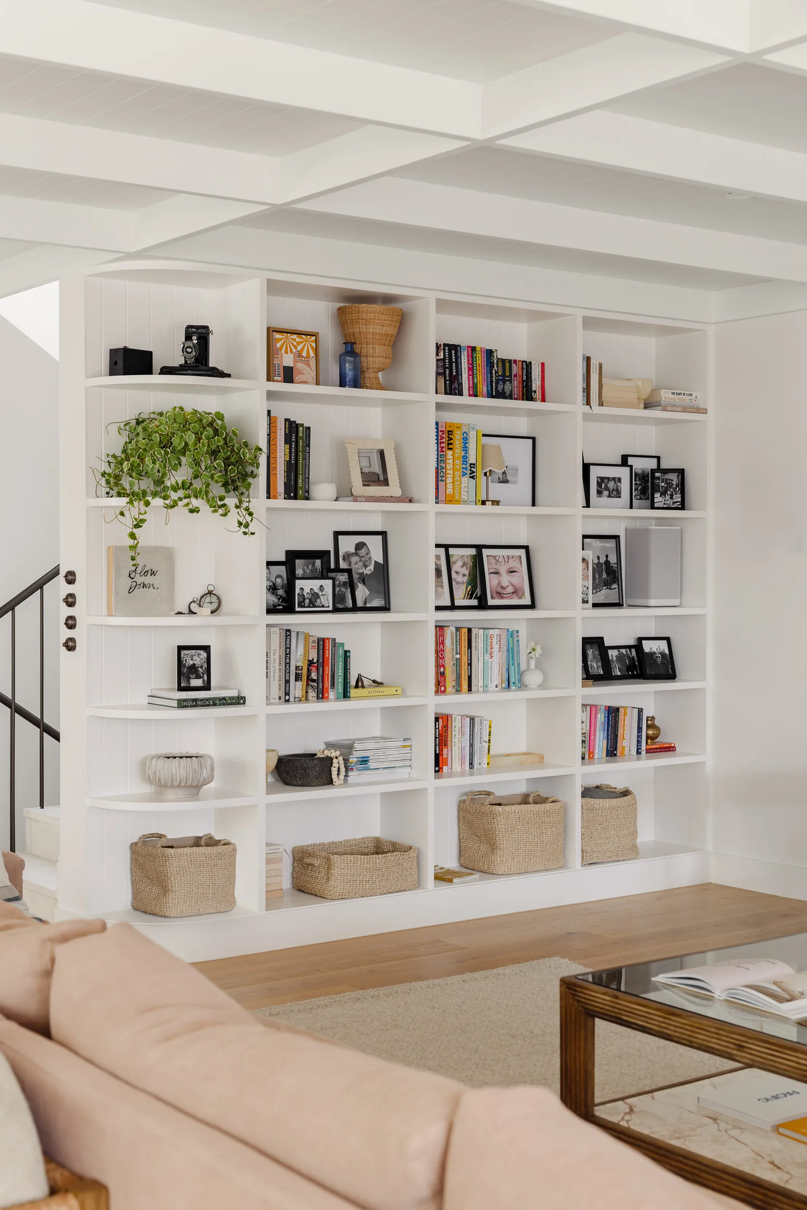 A large bookcase wall filled with books, family photos, plants and treasures.