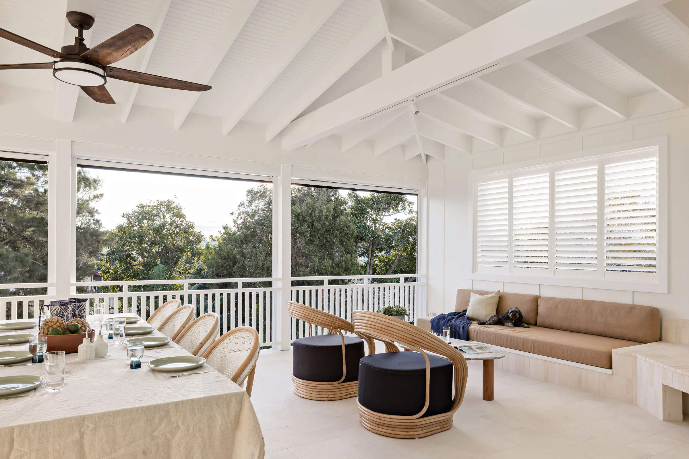 An outdoor entertaining area with a dining area, lounge area and large brass ceiling fan.