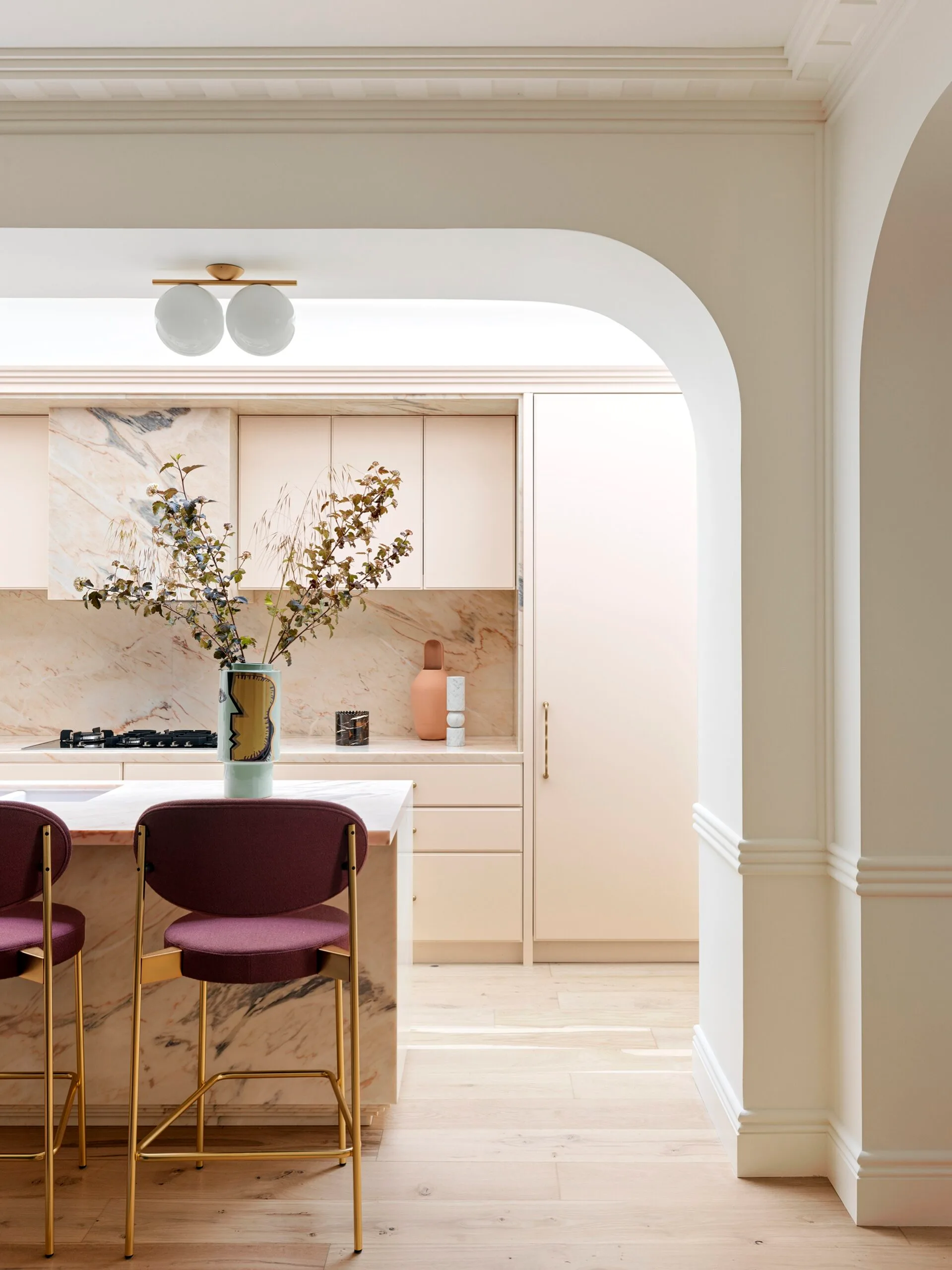 A contemporary kitchen with purple bar stools, curved details and marble finishes
