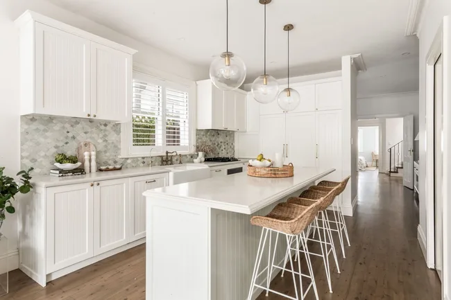 A country-inspired kitchen with rattan bar stools and round pendant lights