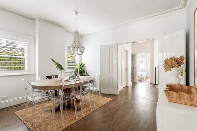 A dining room with acrylic chairs and a chandelier