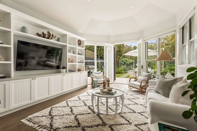 A living area with white furnishings and a large TV cabinet