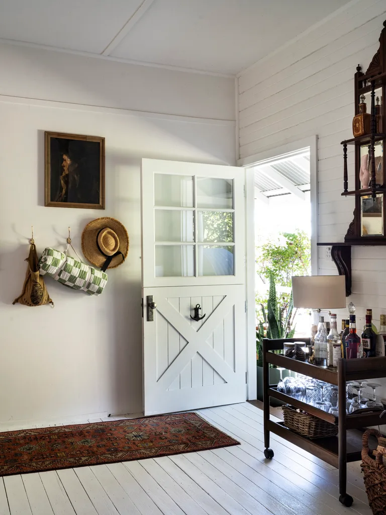 A sun-filled entryway with a bar cart and antique furniture.