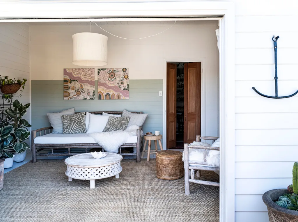 A coastal living room with white walls and rustic furniture. An aboriginal artwork hangs on the wall.